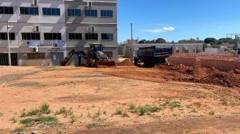 Terreno em preparação para obra, com escavadeira e caminhão basculante