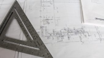 Régua e esquadro sobre planta técnica de arquitetura, representando a etapa de concepção do projeto